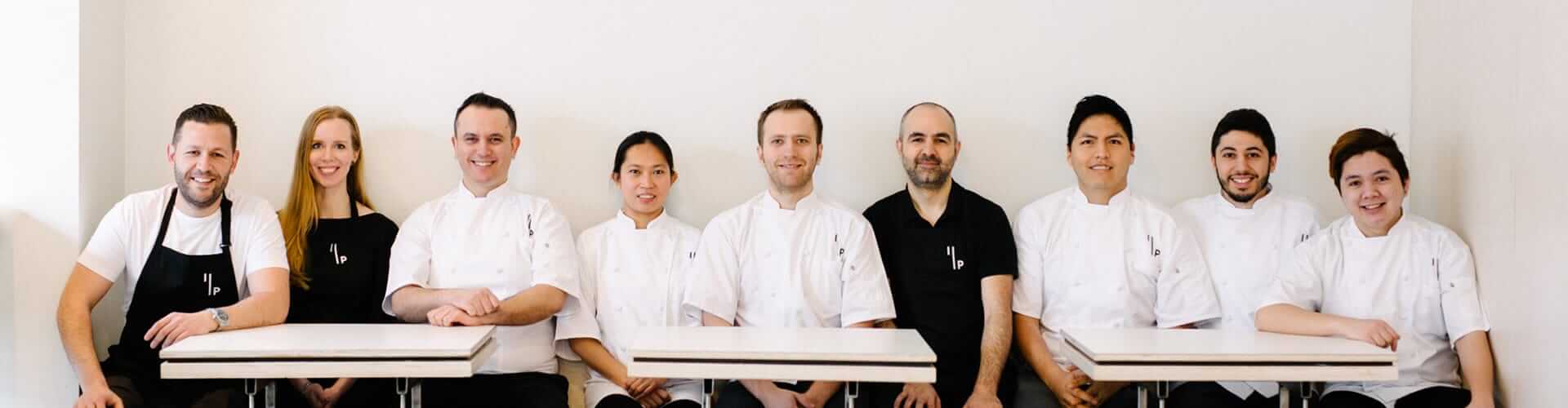 The dedicated team of Ignite Pizzeria, smiling in their kitchen uniforms, ready to serve the best pizza in Vancouver