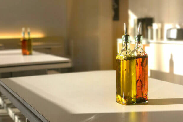 Sunlit bottles of golden olive oil on the counter at Ignite Pizzeria, highlighting the quality ingredients used